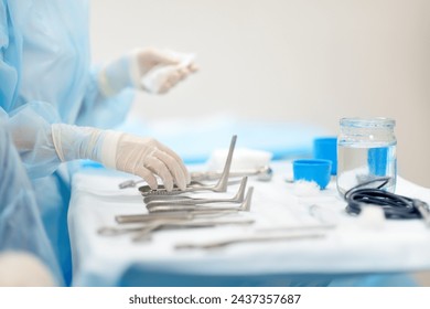 A nurse hands sterile surgical instruments to a doctor during maxillofacial surgery operation. Steel medical instruments are ready to be used. Modern equipment, tools and technology for medicine. - Powered by Shutterstock