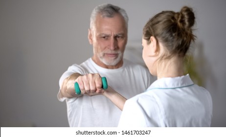 Nurse Helping Old Man To Lift Dumbbell, Cardiac Rehabilitation, Injury Recovery