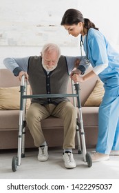 Nurse Helping To Retired Man, Getting Up From Sofa