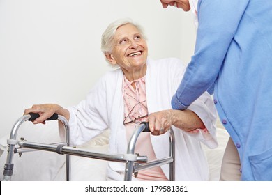 Nurse Helping Senior Citizen Patient In Nursing Home Getting Up