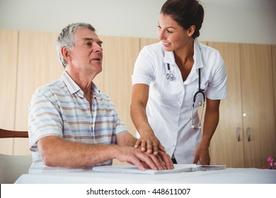 Nurse helping senior man with braille in a retirement home - Powered by Shutterstock