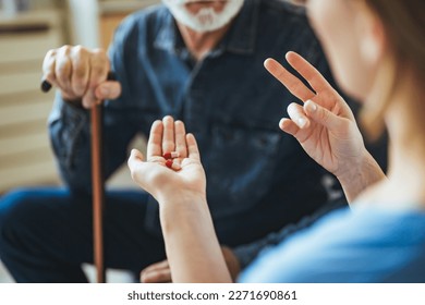 Nurse Helping Senior Man To Organize Medication On Home Visit. Nurse giving senior man prescription drugs. Senior male patient consult with physician nurse at nursing home. - Powered by Shutterstock