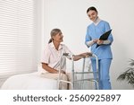 Nurse helping senior woman with walking frame in clinic