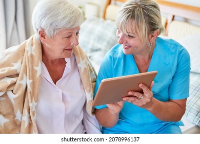 Nurse Helps Senior Woman Video Chat On Tablet Computer In Nursing Home Or At Home