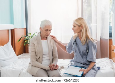nurse holding clipboard and looking at upset senior woman sitting on hospital bed - Shutterstock ID 726141283