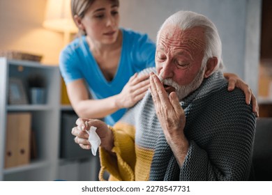 Nurse holding hands of senior man in living room. Young ill man lying in bed at home. Adult woman caring for sick man. Woman checking fever temperature of senior man lying on bed.  - Powered by Shutterstock