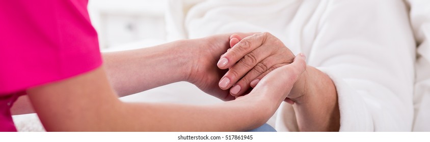 Nurse Holding Older Woman's Hand In Nursisng Home