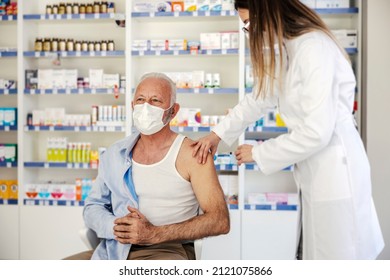 A nurse injecting corona virus vaccine into a senior's man shoulder at pharmacy. - Powered by Shutterstock