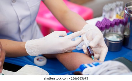 Nurse injecting with syringe to patient's arm drawing blood sample for blood test in hospital.                               