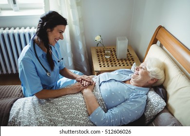 Nurse interacting with senior woman on bed at bedroom - Shutterstock ID 512606026