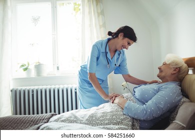 Nurse interacting with senior woman on bed at bedroom - Shutterstock ID 584251660
