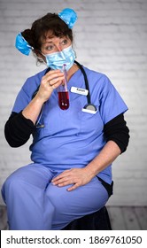 Nurse Karen Wearing A Mask On Her Face And In Her Hair While Drinking Red Fluid From A Test Tube. 