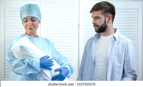 Nurse looking at child before giving baby to father, leaving maternity hospital - Powered by Shutterstock