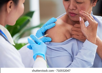 Nurse Making Injection Into Shoulder Of Senior Woman