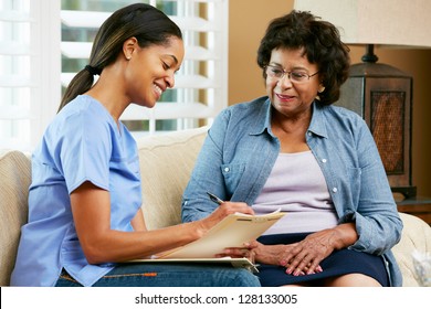Nurse Making Notes During Home Visit With Senior Female Patient