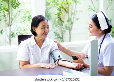 Nurse Measuring Blood Pressure Of Senior Woman At Home. Health Insurance Concept