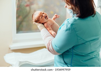 Nurse with newborn baby in postpartum ward. Maternity hospital, doctor and nurse neonatologist. Medical staff and the newborn in the first hours of life.