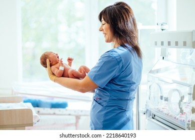 Nurse With Newborn Baby In Postpartum Ward. Maternity Hospital, Doctor Or Nurse Neonatologist.