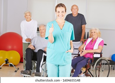 Nurse in nursing home holds thumbs up with a group of seniors in the background - Powered by Shutterstock