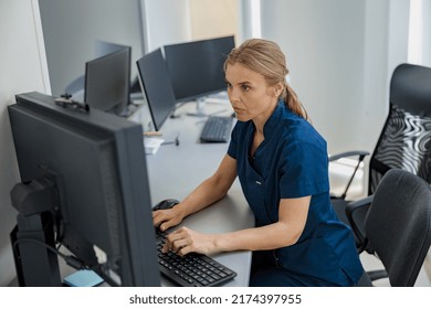 Nurse On Duty Working On Computer At The Reception Desk In Modern Clinic. High Quality Photo