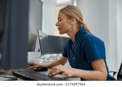 Nurse On Duty Working On Computer At The Reception Desk In Modern Clinic. High Quality Photo