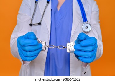 A Nurse On A Red Background Shows Hands In Handcuffs, Closeup. Doctor Arrested For A Bribe From A Patient, Concept