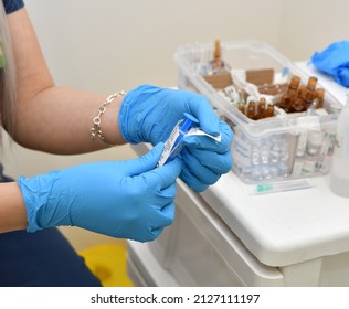 Nurse Opening New Syringe With Blue Plastic Gloves On