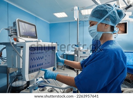 Nurse in operating room of hospital checking patient's vital signs while surgical operation. Surgical department