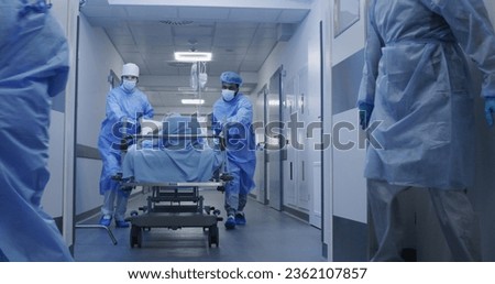Nurse and paramedic open medical facility corridor doors. Multi ethnic surgeons push stretcher with lying elderly patient to operating room. Medical personnel work in emergency department. Slow motion ストックフォト © 