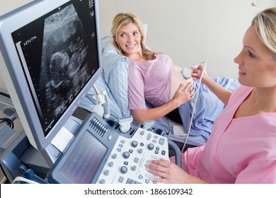 Nurse performing ultrasound on a smiling pregnant woman in the hospital Stock Photo