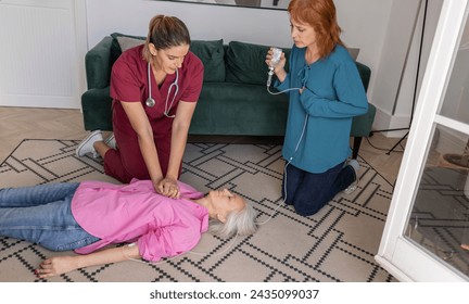 A nurse performs CPR on an elderly lady at home as another adult prepares an injection. - Powered by Shutterstock