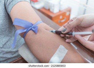 A Nurse Or Phlebotomist Draws Blood From The Vein Of A Patient. An IV Tourniquet Placed Above The Elbow. Venipuncture For Blood Testing Or Hematology Analysis.