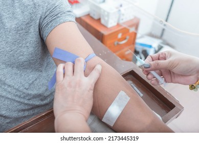 A Nurse Or Phlebotomist Getting Ready To Draw Blood From The Vein Of A Patient. An IV Tourniquet Placed Above The Elbow. Venipuncture For Blood Testing Or Hematology Analysis.