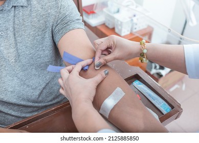 A nurse or phlebotomist rubs the vein area of patient with alcohol prior to venipuncture. An IV Tourniquet placed above the elbow. For blood testing or hematology analysis.