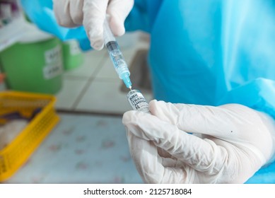 A Nurse In Ppe Gear Draws Tramadol HCL From An Ampule Into A Syringe. Preparing To Inject Opioid Pain Medication. Hospital Or ER Scene.