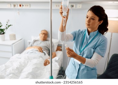 Nurse practitioner checking IV drip of elderly patient at hospital ward - Powered by Shutterstock