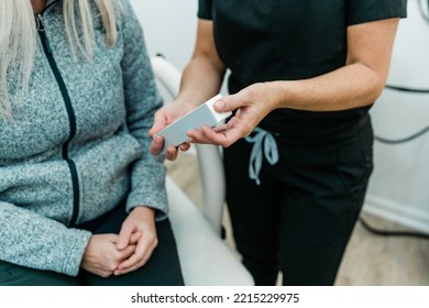 A Nurse Practitioner At A Medical Wellness Spa Showing An Anti-aging Skincare Product To The Patient Or Client.