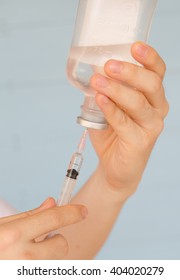Nurse prepares to draw  normal saline from plastic bottle
