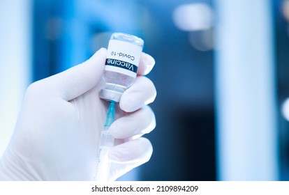 A Nurse In Protective Blue Medical Gloves Holds A Vial Of Vaccine And A Syringe. Coronavirus Vaccine. Medicine, Healthcare And Science Concept.
