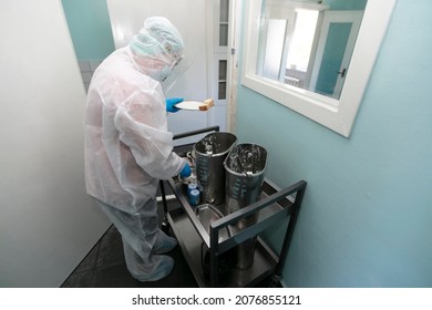 A nurse in a protective suit distributes food during a coronavirus infection. Hospital meals. - Powered by Shutterstock