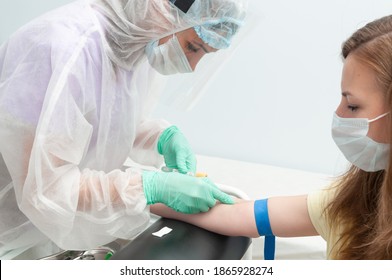 A nurse in a protective suit takes blood from a girl's vein. Pandemic. Analysis for antibodies to the coronavirus. Vaccination.