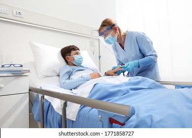 Nurse With Pulse Oximeter On Patient Child In Hospital Bed, Wearing Protective Visor Mask, Corona Virus Covid 19 Protection Concept, 