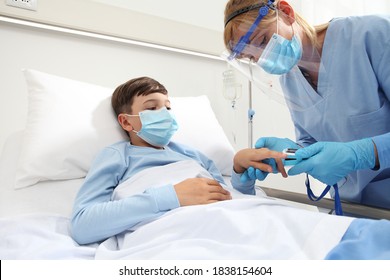 Nurse With Pulse Oximeter On Patient Child In Hospital Bed, Wearing Protective Visor Mask, Corona Virus Covid 19 Protection Concept, 