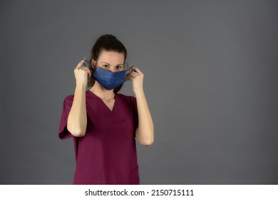 Nurse In Purple Scrubs While Removing Surgical Mask