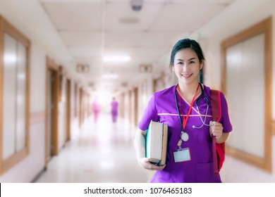 nurse in purple uniform with backpack standing and holding  books.Nurse, Student, Education