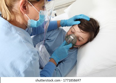 Nurse Puts Oxygen Mask On Patient Child In Hospital Bed, Wearing Protective Visor Mask, Corona Virus Covid 19 Protection Concept, 