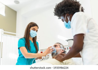 Nurse puts oxygen mask on elderly man patient lying in the hospital room bed while African American doctor examining patient with stethoscope, coronavirus covid 19 protection concept - Powered by Shutterstock