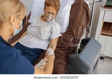 Nurse Putting Drip On The Arm Of Her Patient In Mask During Pandemic Of Covid 19. High Quality Photo