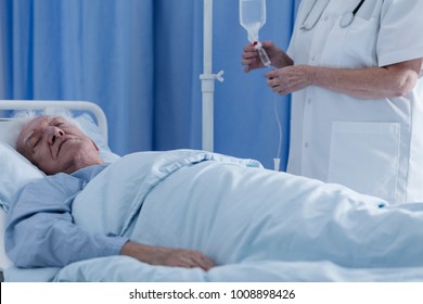 Nurse Putting A Dying, Senior Patient On A Drip In A Hospital