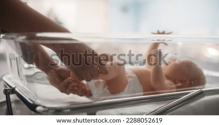Nurse Putting Identification Hospital Name Tag on a Newborn Caucasian Child. Healthy Infant Baby Lying in a Maternity Clinic, Waiting for Mother to Recover After Childbirth